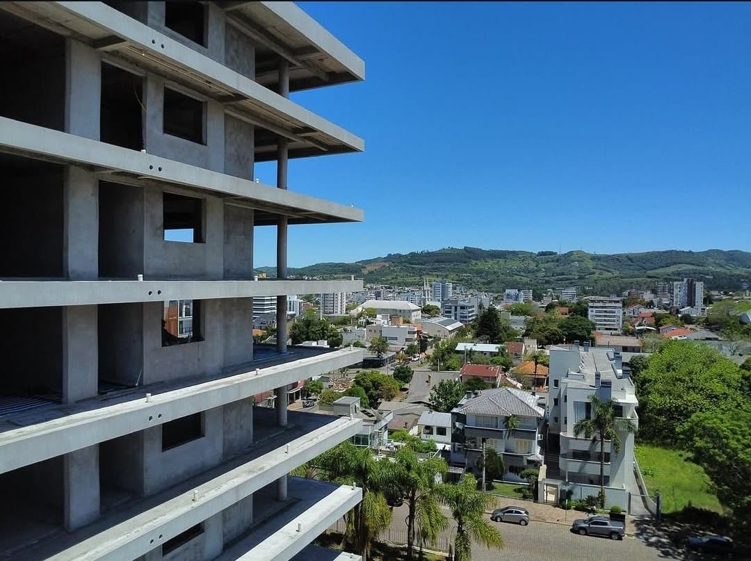 Estrutura de edifício em construção com vista para a cidade e os morros ao fundo