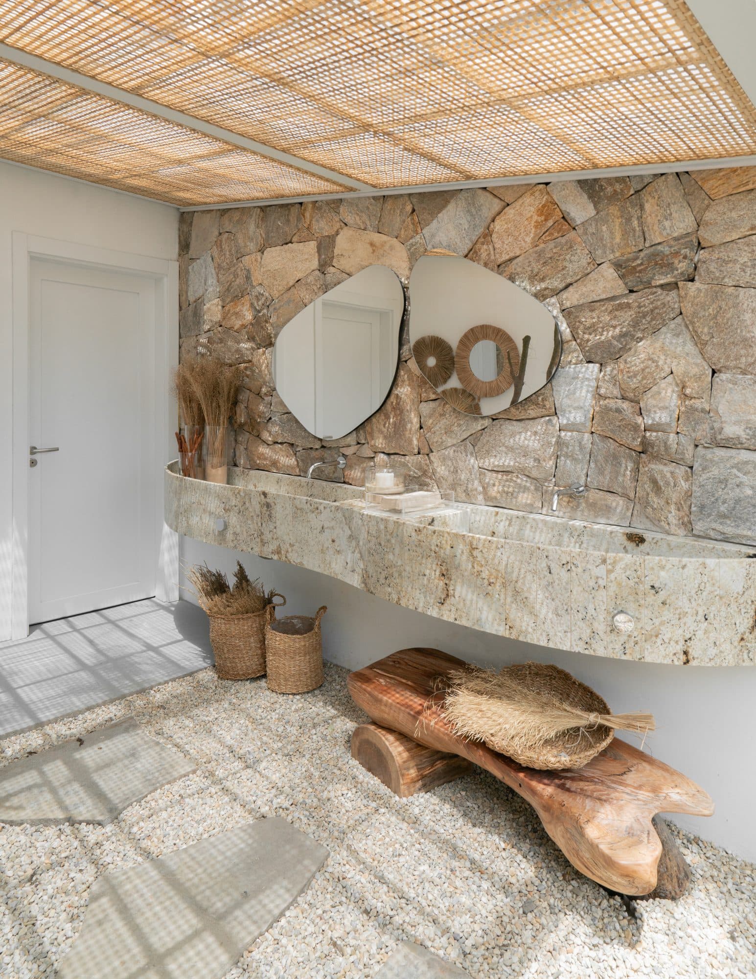Lavabo com parede de pedra e porta lisa branca em residência de alto padrão